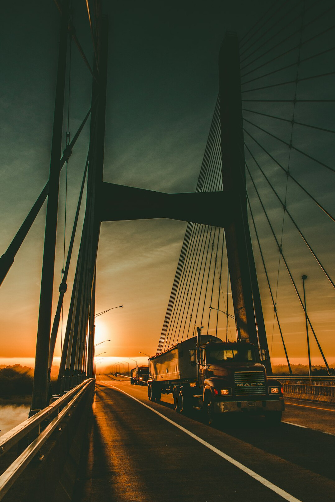Delivery trucks driving on a highway at dusk